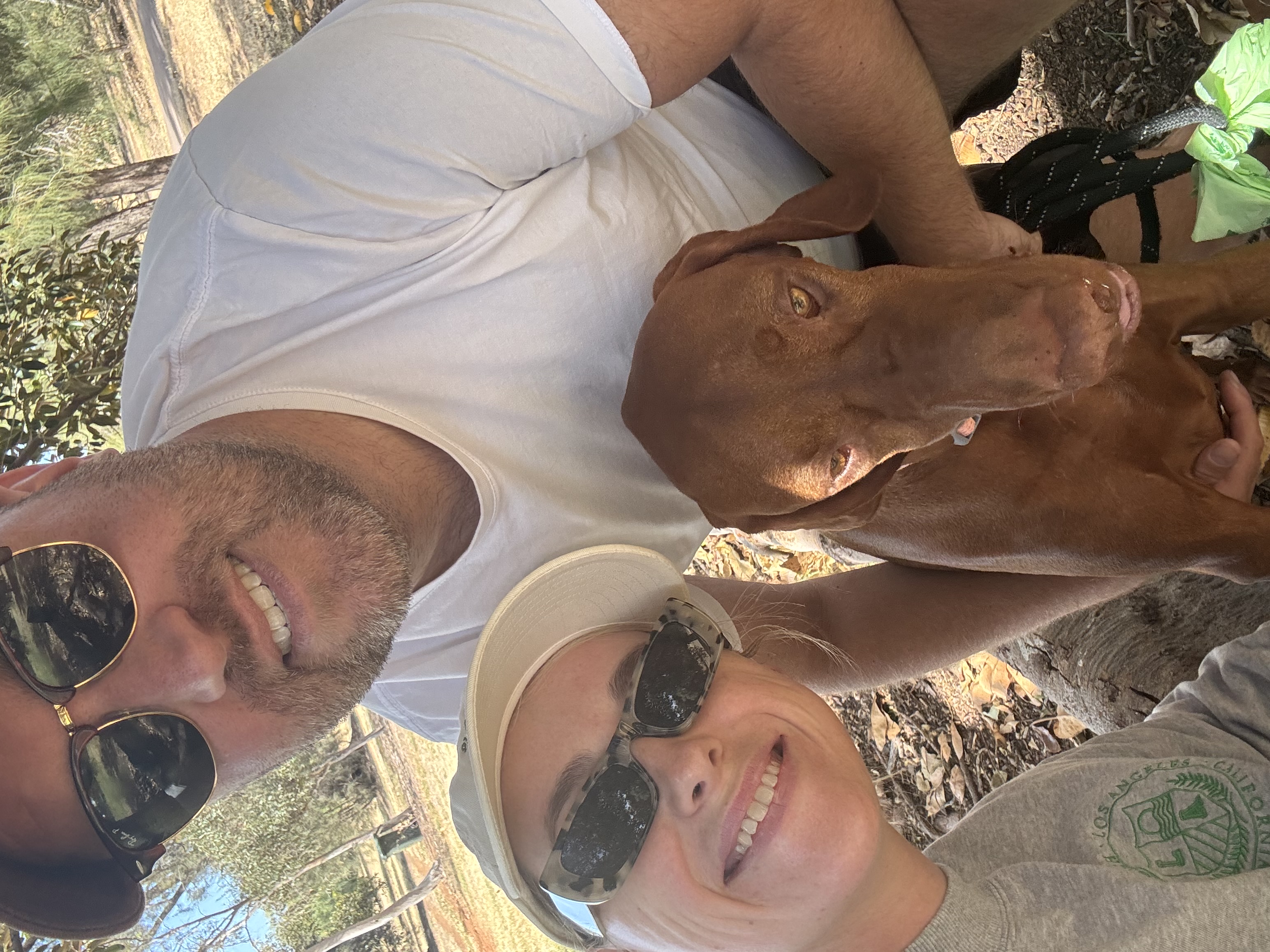 Tim, Kayleigh and Nelson the Vizsla, smiling in a park